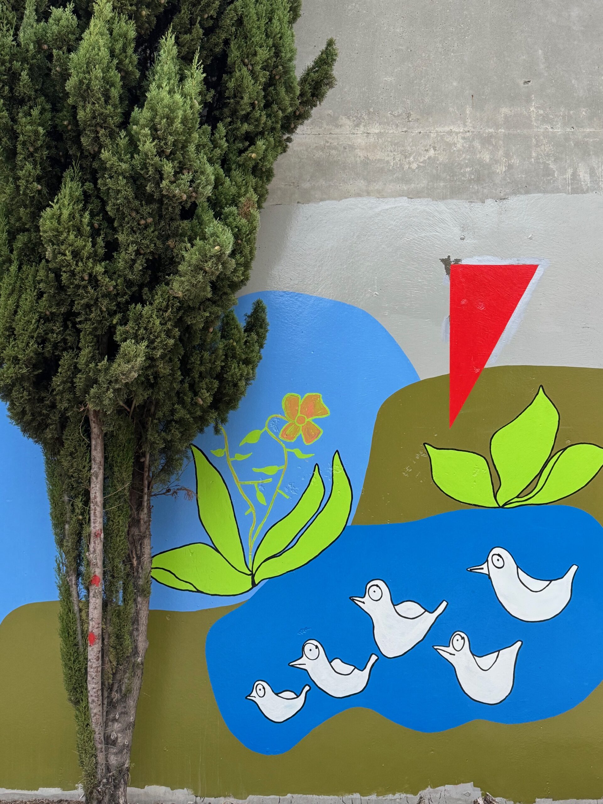 Street art mural of white birds and green leaves on a blue and grey wall