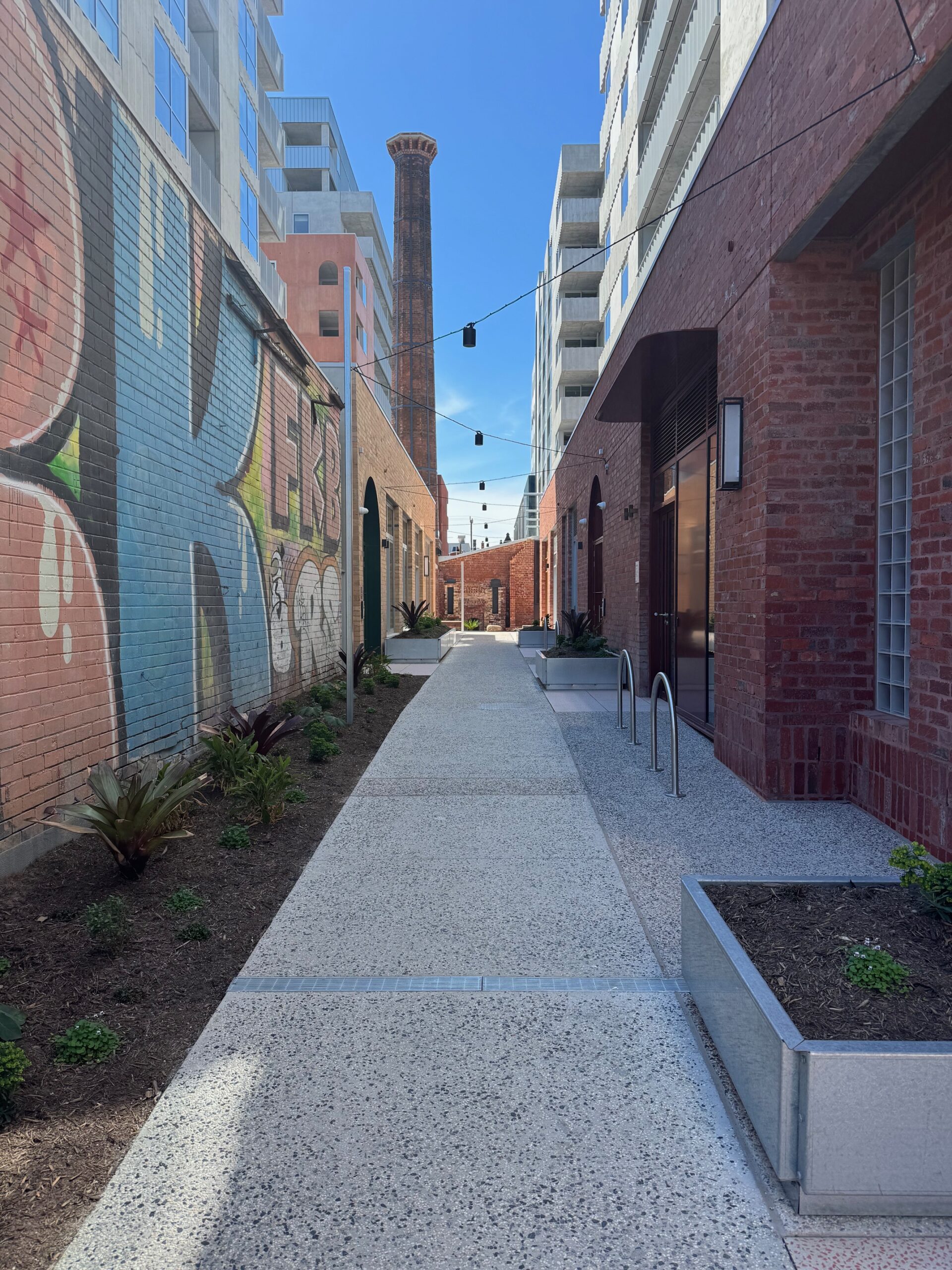 Melbourne laneway with street art murals and brick buildings under a blue sky